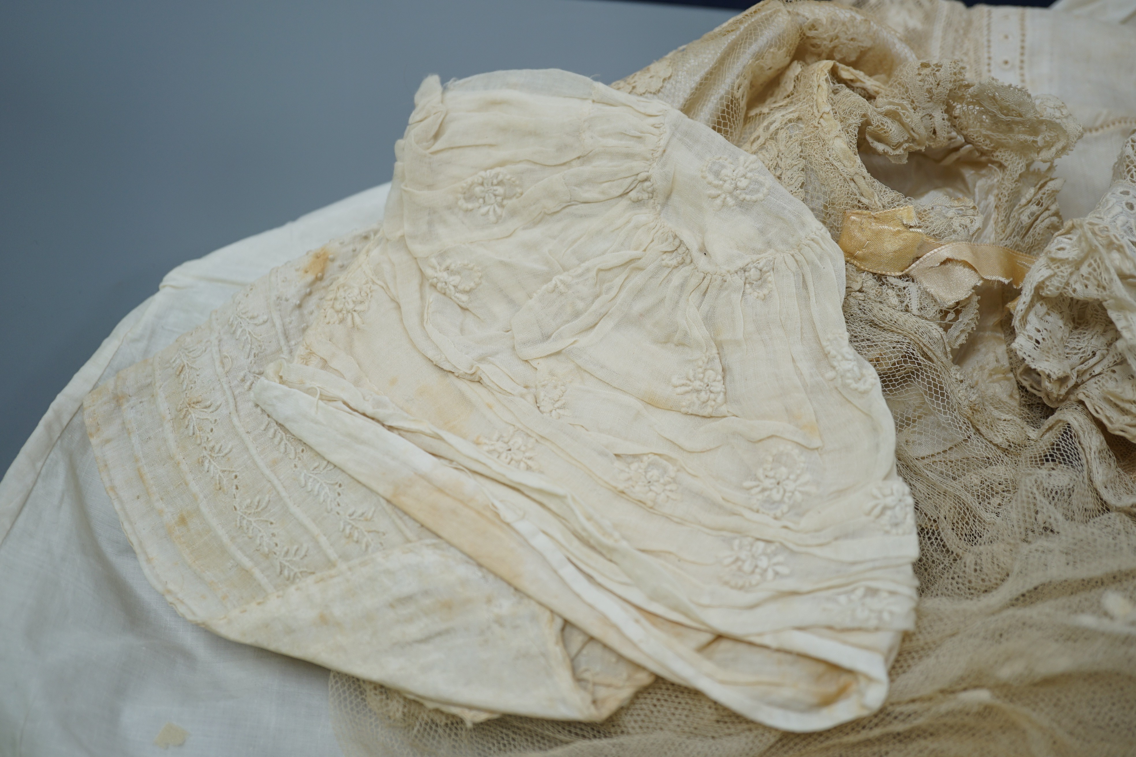 A collection of 19th century babywear, lace and cutwork bonnets and a christening bonnet and veil